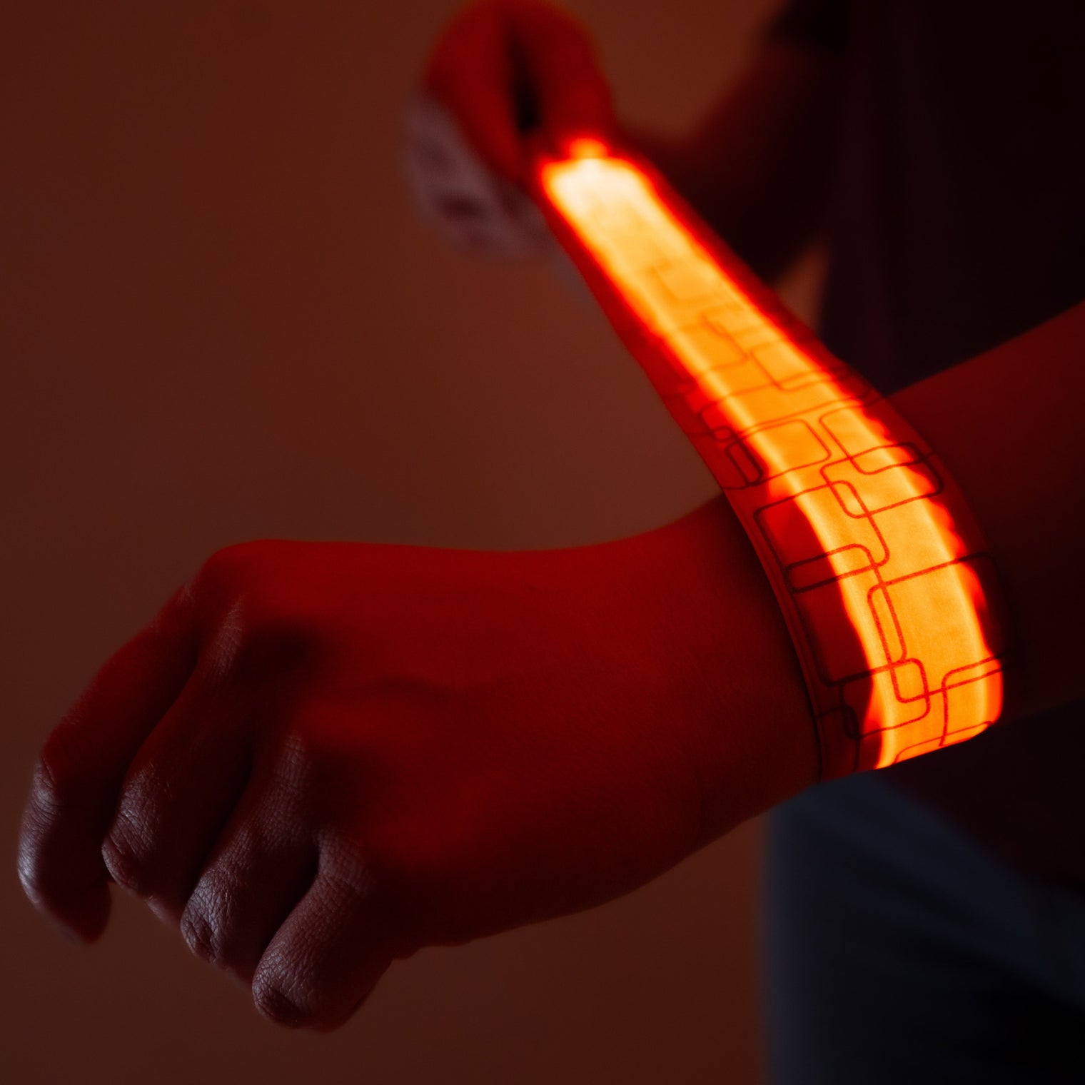 Person wearing a glowing orange LED slap bracelet