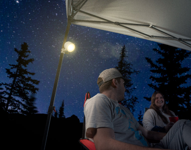 Two people under a tent canopy being illuminated by LED canopy spotlight
