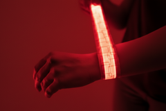 Person wearing a glowing red LED slap bracelet against a dark background
