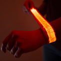 Person wearing a glowing orange LED slap bracelet