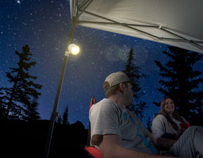 Two people under a tent canopy being illuminated by LED canopy spotlight