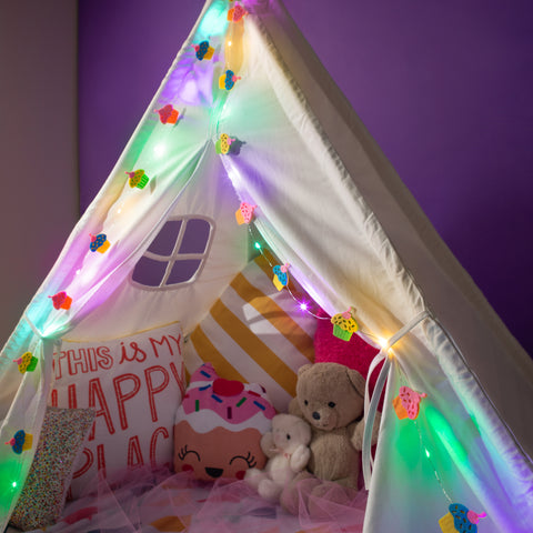 Children's play tent with colorful cupcake lights and stuffed toys against a purple wall.