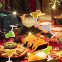 Decorative string lights shaped like cocktail glasses over a festive table with food and drinks.