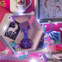 Unicorn-themed lights and stationery items on a pink surface with a laptop.