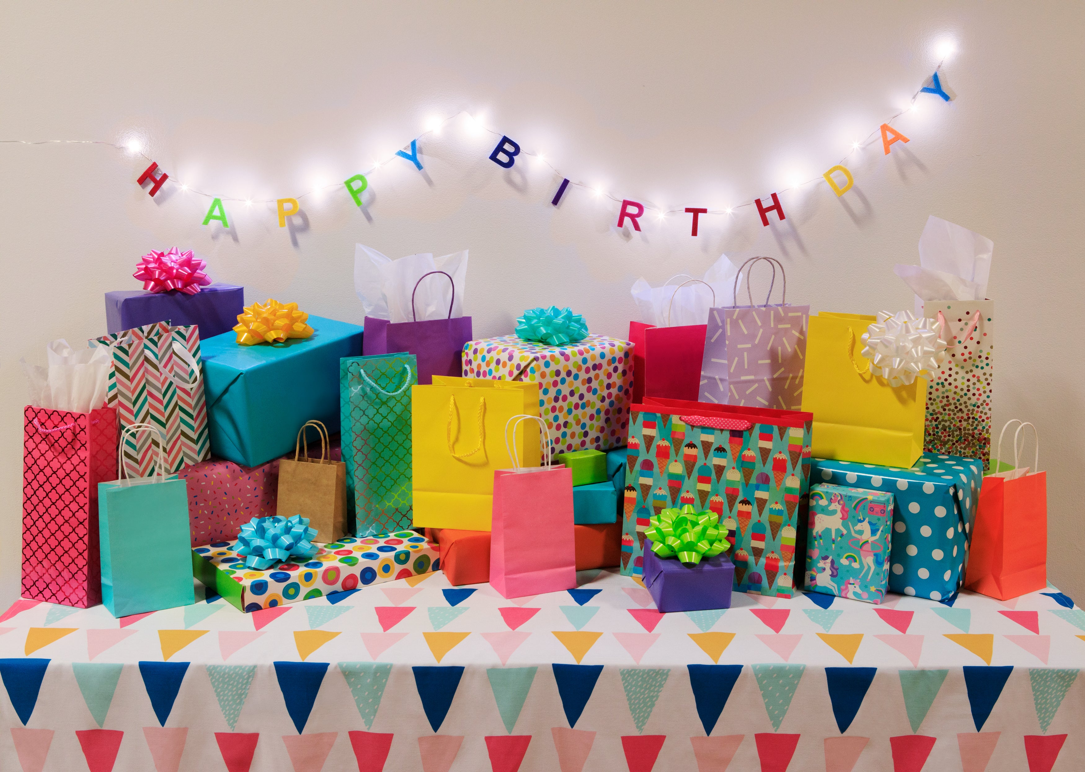 Colorful birthday gifts and decorations on a table with 'Happy Birthday' banner.