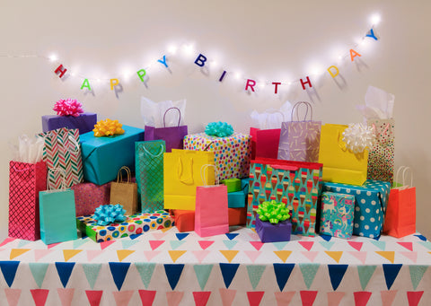 Colorful birthday gifts and decorations on a table with 'Happy Birthday' banner.