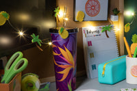 Colorful desk setup with pineapple tropical LED Lights, a purple tumbler, green scissors, and decorative items.