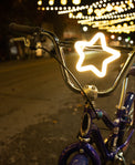 Bicycle with a star-shaped light on the handlebar against a night-time street background.