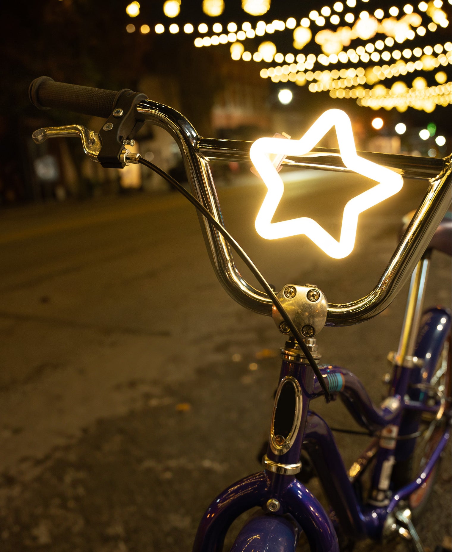 Bicycle with a star-shaped light on the handlebar against a night-time street background.
